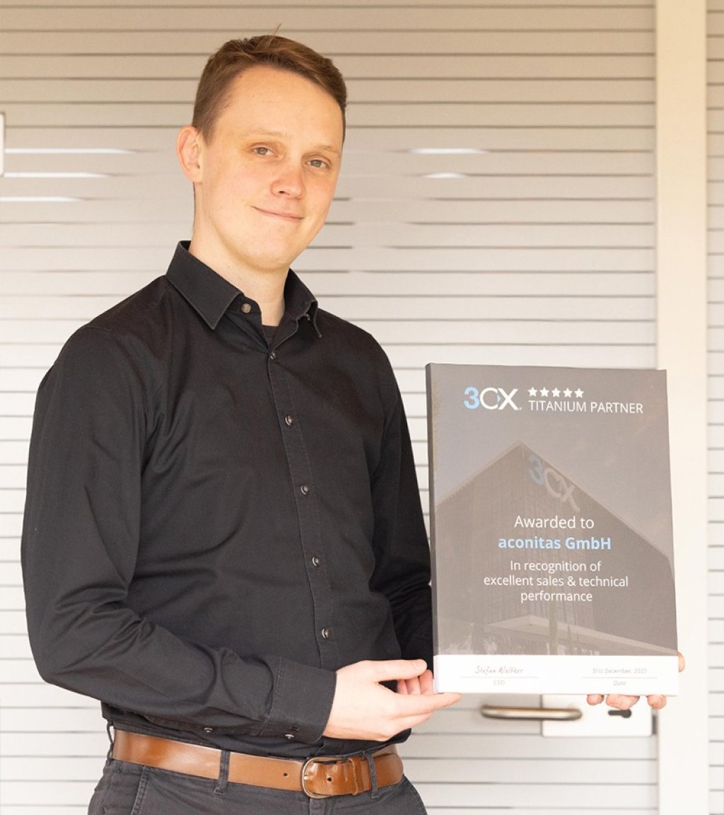 Der Mitarbeiter Tim Starke von der aconitas GmbH hält in seinen Händen das Titanium Partner-Zertifikat von 3CX, das aconitas für die Leistungen im Verkauf und durch technische Expertise erhalten hat.