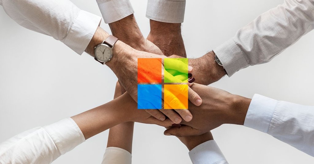 Mehrere Hände liegen übereinander. Über den Händen ist das Logo von Microsoft platziert.