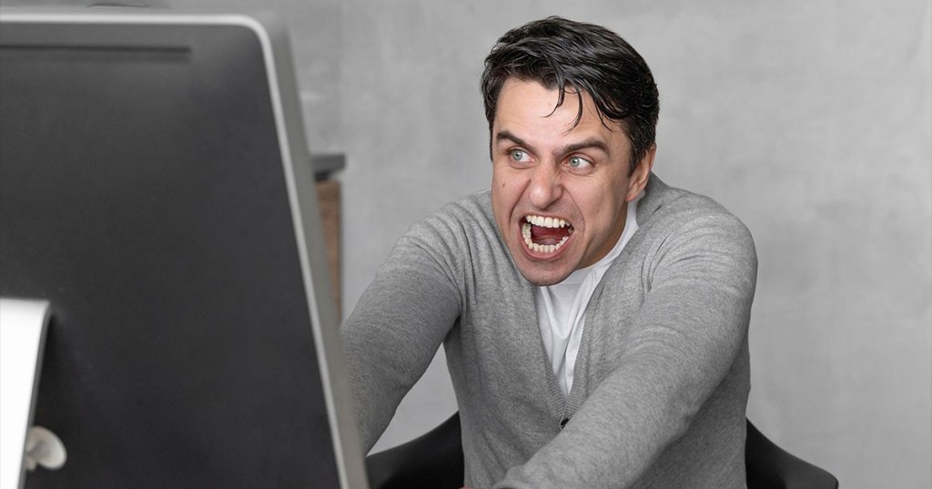 Ein Mann schreit vor seinem Laptop.